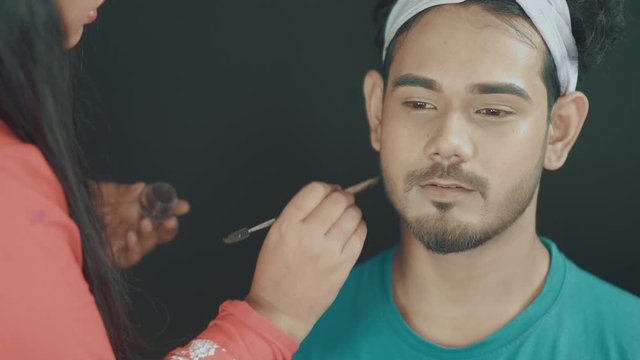 Close up of professional make up artist fixing mans beard and doing the make up 