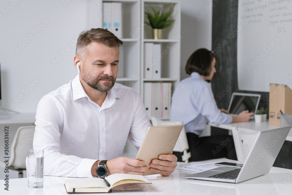Poster serious office worker looking at touchpad display while watching online training