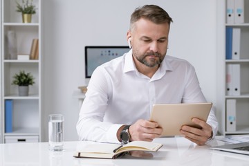 Serious businessman looking at touchpad display while watching online conference