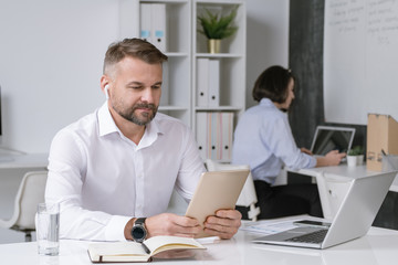 Serious office worker looking at touchpad display while watching online training