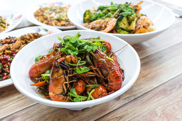 Chongqing Sichuan spicy dried chilli small lobsters, among other dishes in the background. Food photography at Chinese restaurant.