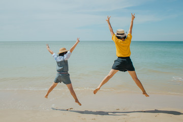 Obraz premium Summer Vacation and Travel Trip Concept : Woman and child felling happiness, they jumping on sand beach.