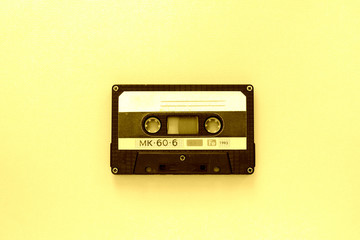 Old audio tape cassette, top view. Old technology concept. Yellow color toned