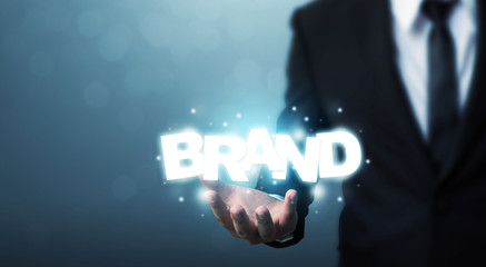 Branding idea concept. Businessman hand holding word BRAND with bokeh background