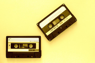 Fototapeta premium Two audio tape cassettes, top view. Old technology concept. Yellow color toned