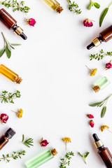 Natural wellness. Essential oils near herbs and leaves on white background top view pattern frame copy space