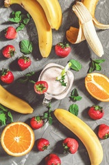 banana, strawberry and orange smoothies with mint in a glass with a straw on the table, top view - 306834452