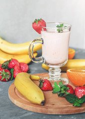 banana, strawberry and orange smoothies with mint on the table, front view - 306834464