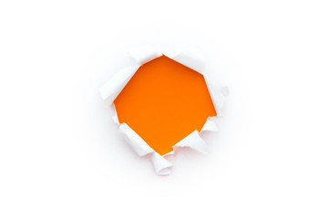 A round hole in white paper with torn edges isolated on a white background with a bright orange...