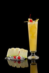 Vertical image of  screwdriver cocktail with orange juice and vodka decorated with cherry and melon isolated at black background.