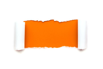 A hole in white paper with torn edges isolated on a white background with a bright orange color paper background inside.