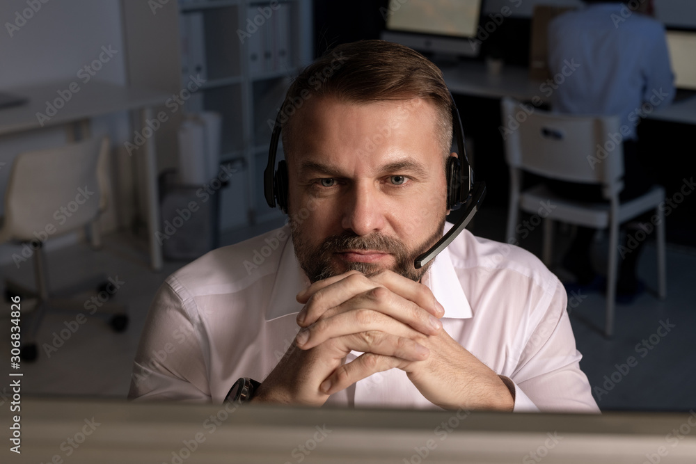 Poster confident manager with headset looking at computer screen during consultation