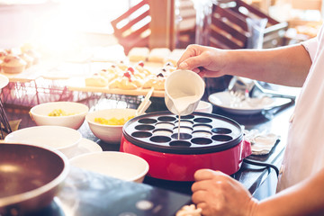 The chef make the dessert on the table and pour coconut milk.