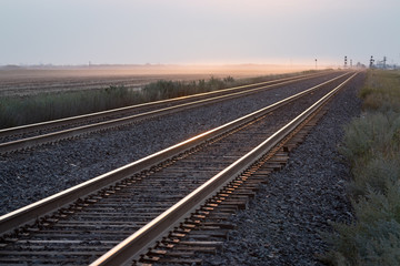 Fototapeta na wymiar Empty Pair of Railroad Tracks at Sunrise on the Prairie