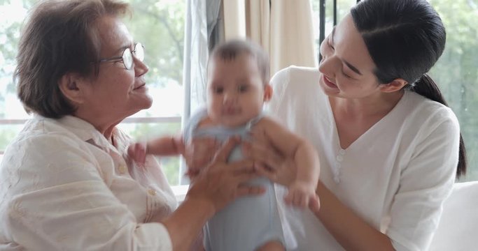 Mother and Grandmother playing with baby together with smile at home. Family and lifestyle concept.