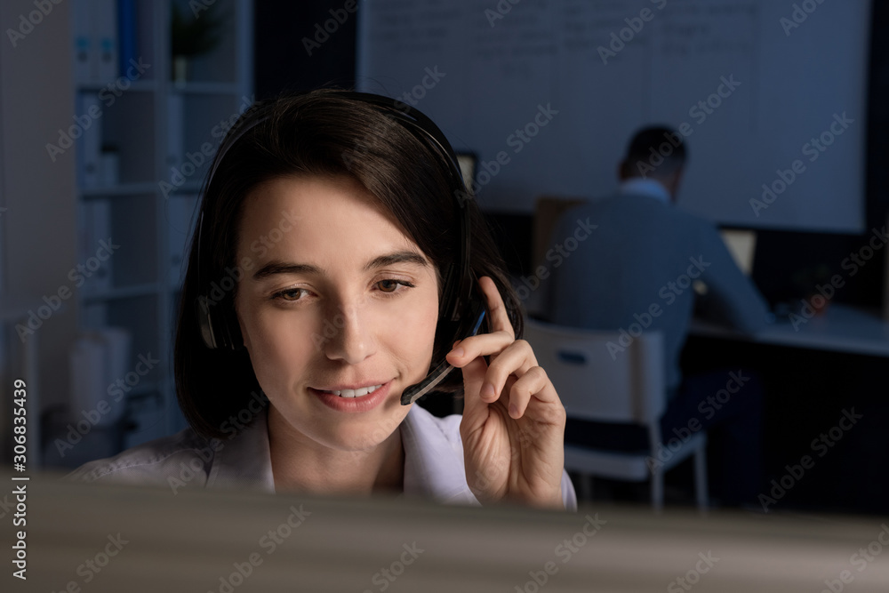 Aufkleber young smiling brunette operator with headset looking at computer screen