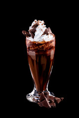 Vertical image of glass of chocolate milkshake decorated with whipped milk isolated at black...