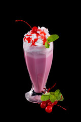 Vertical image of cherry milkshake cocktail decorated with mint isolated at black background.
