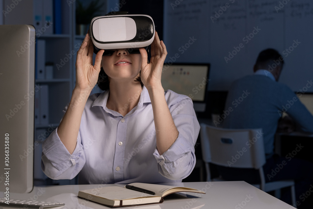 Poster young office worker with vr headset sitting by desk in front of computer