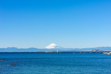 雪をかぶった富士山を相模湾岸に望む