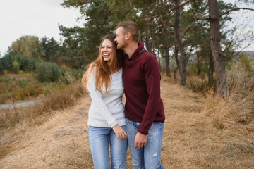 Couple in love lying on a picnic blanket in a park, enjoying beautiful autumn day in nature and cuddling