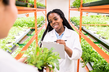 Happy young woman of African ethnicity making notes in document