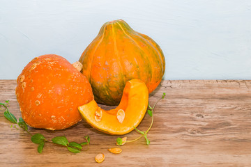 A slice of orange, yellow pumpkin and a whole pumpkin on an old wooden table. The concept of healthy eating. Vegetarian and vegan food.Vegetable diet.Still life for Halloween with copy space, space fo