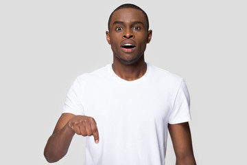 Surprised African American man with open mouth pointing finger down © fizkes