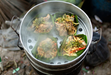 Thai food wrapped in banana leaves on a charcoal stove