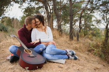 Couple in love lying on a picnic blanket in a park, enjoying beautiful autumn day in nature and cuddling