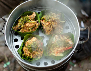 Thai food wrapped in banana leaves on a charcoal stove