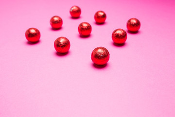 Chocolates in a multi-colored foil on a pink background
