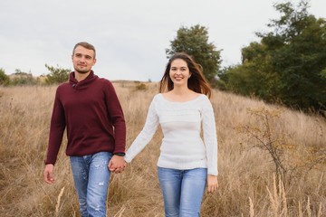 Couple in love lying on a picnic blanket in a park, enjoying beautiful autumn day in nature and cuddling