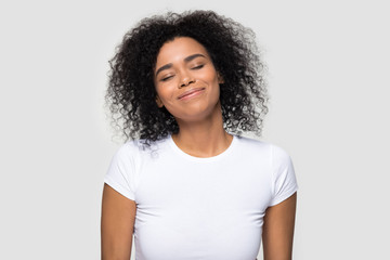 Satisfied African American woman enjoying, dreaming with closed eyes