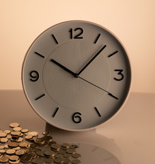 White clock and coins on corner beige background