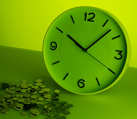White clock and silver coins on green background