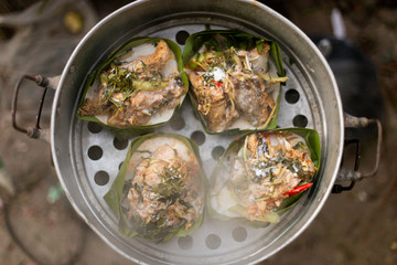 Thai food wrapped in banana leaves on a charcoal stove
