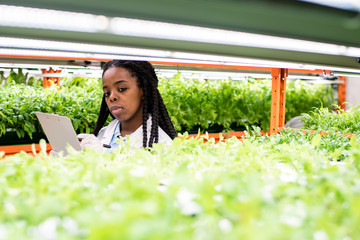 Young gloved African biologist making notes while standing among shelves