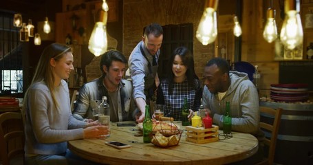 Slow motion of friends are served by a waiter with italian pizza and drinking beer at restaurant or pub. Shot in 8k. Concept of college friends, holidays, food and drink - Powered by Adobe