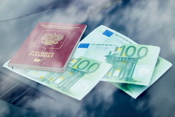 Euro banknotes and red passport on the dashboard and their reflection in the windshield inside of a car