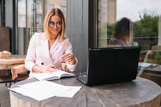 Portrait of young attractive businesswoman examining paperwork in bight light office interior sitting next to the window, business woman read some documents before meeting, filtered image