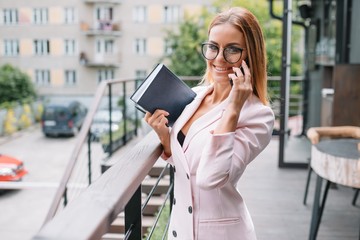 Business woman on the phone at office. Young business woman having phone call at the office. Smiling business woman. Pretty young business using smartphone at the loft office.