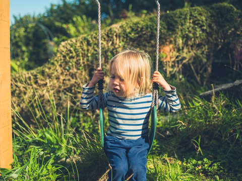Little toddler on swing in garden