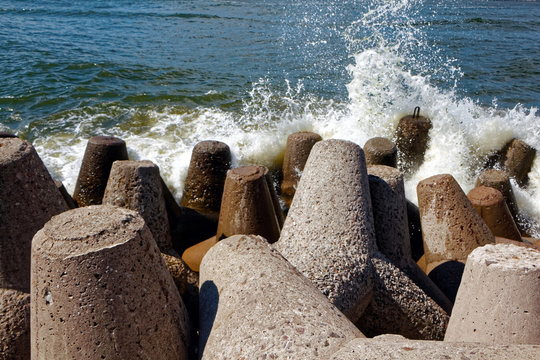 The sea waves are beating against concrete breakwaters