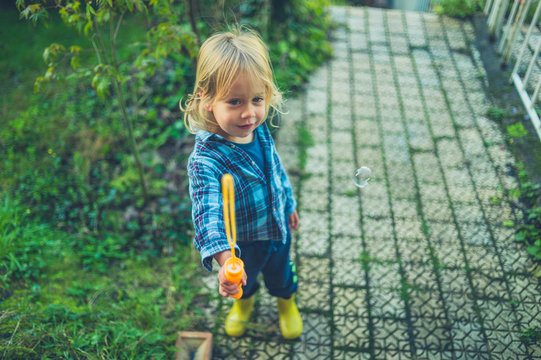 Toddler blowing bubbles in the garden