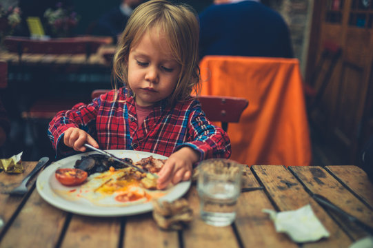 Toddler eating english breakfast in cafe