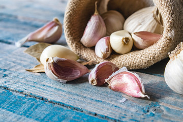 Cloves of garlic and whole garlic in a bag on a blue rustic table.