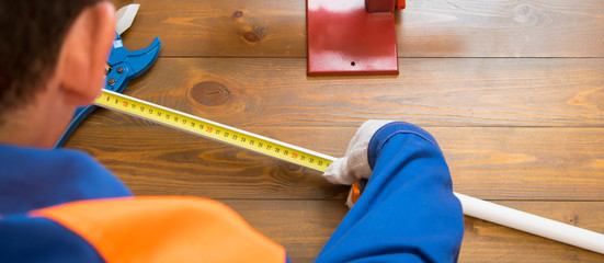 hand of the master measuring tape measure the pipe before installing the plumbing on wooden...