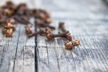 The spice of dried cloves lies on a pile on old wooden boards.