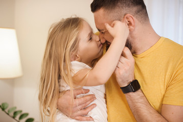 Close up of a lovely little kid playing with her father at home. Cute little girl boxing with her father.